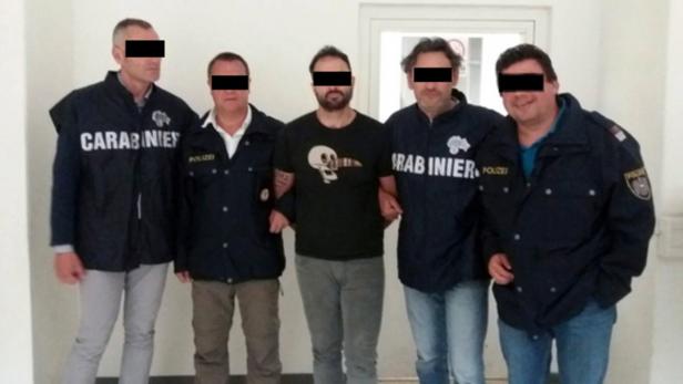Ein Mann wird von zwei Carabinieri und zwei Polizisten abgeführt.