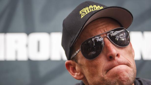 Ein Mann mit Sonnenbrille und Kappe vor einem „Ironman“-Logo.
