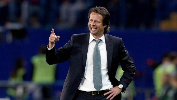 Ein Mann in Anzug gestikuliert und lächelt.