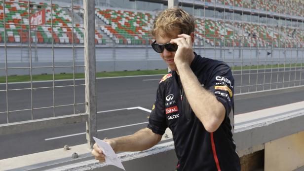 Sebastian Vettel betrachtet eine Zeichnung an einer Rennstrecke.