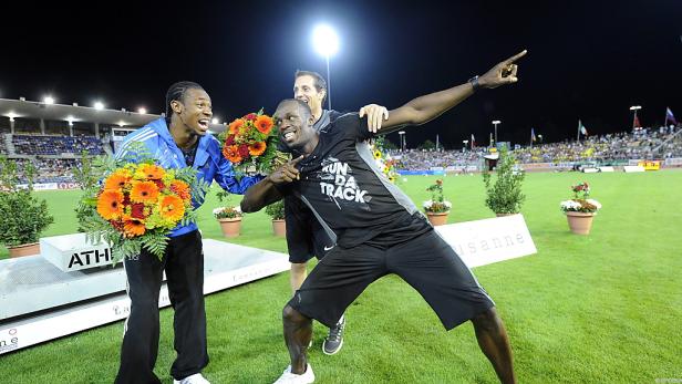 Usain Bolt und ein weiterer Athlet feiern mit Blumen auf dem Siegerpodest in Lausanne.