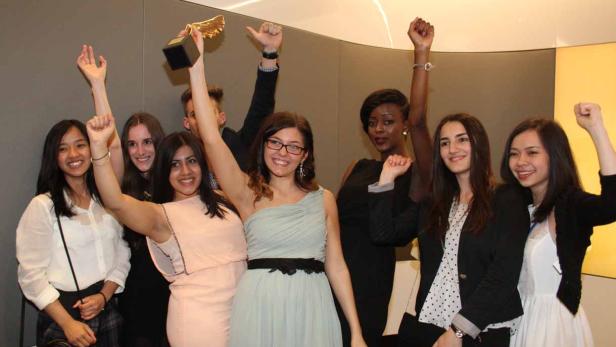 Eine Gruppe junger Leute jubelt mit erhobenen Armen und einer goldenen Trophäe.