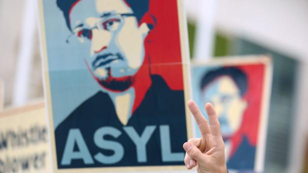 Eine Person demonstriert mit einem Plakat von Edward Snowden, auf dem „ASYL“ steht.