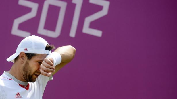 Ein Tennisspieler wischt sich den Schweiß von der Stirn vor dem Hintergrund der Olympischen Spiele 2012.