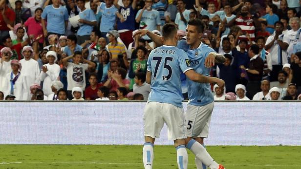 Zwei Fußballspieler von Manchester City feiern vor einer jubelnden Menge.