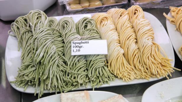 Auf einer Platte liegen grüne und gelbe Spaghetti zum Verkauf.