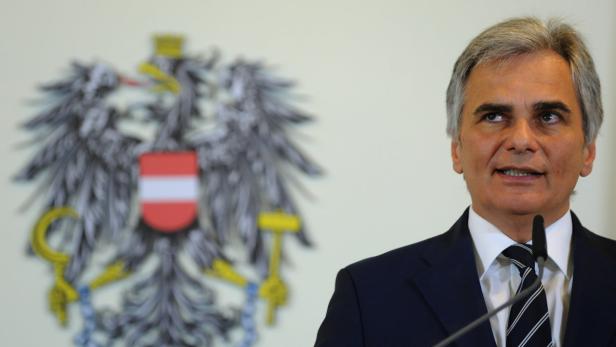 Ein Mann spricht vor dem österreichischen Bundeswappen.