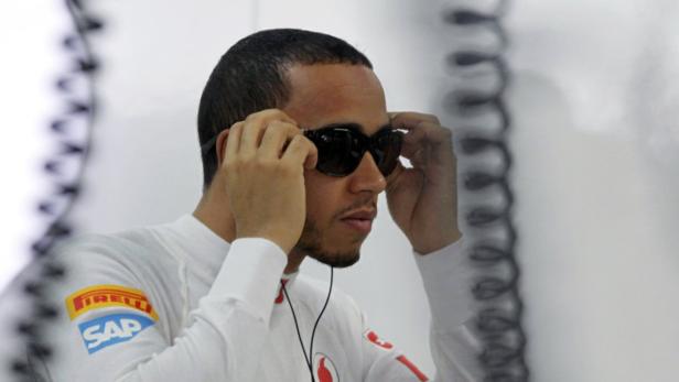 Lewis Hamilton setzt eine Sonnenbrille auf.