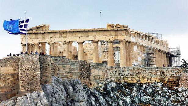 Die Akropolis in Athen mit der griechischen Flagge im Wind.