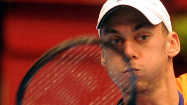 Ein Tennisspieler mit weißer Kappe schlägt einen Ball.