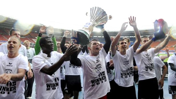 Eine Fußballmannschaft feiert mit der Trophäe den Gewinn des Samsung Cup 2013.