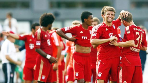 Thomas Müller umarmt Bastian Schweinsteiger und lacht.