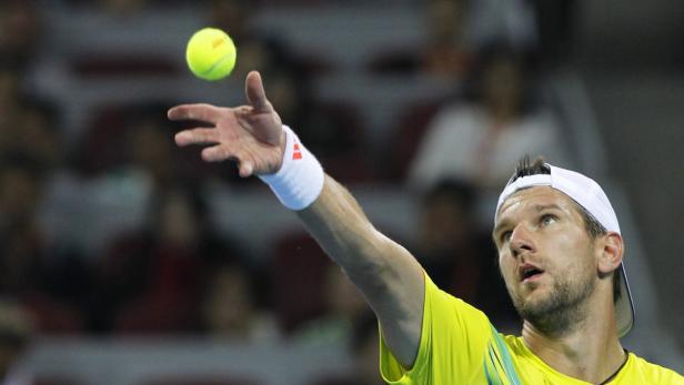 Ein Tennisspieler wirft einen Tennisball zum Aufschlag hoch.