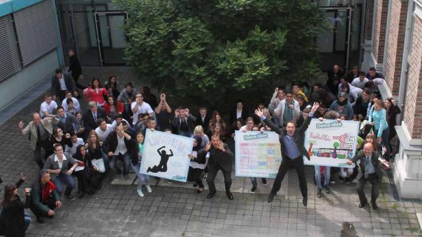 Eine Gruppe von Menschen hält Schilder mit der Aufschrift „Luftsprung“ und „Deine Idee“.