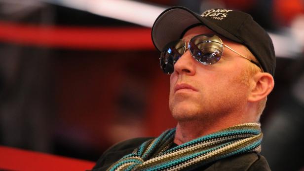 Ein Mann mit Sonnenbrille und Schal trägt eine Kappe mit der Aufschrift „PokerStars.net“.