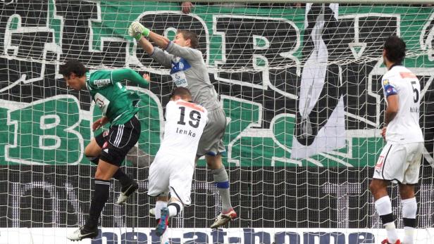 Ein Fußballtorwart springt, um einen Ball während eines Spiels abzuwehren.