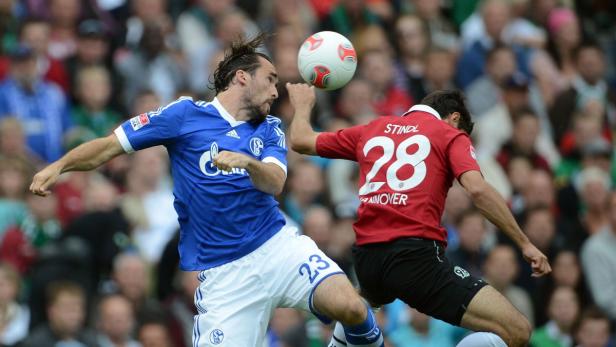 Zwei Fußballspieler kämpfen um den Ball während eines Spiels.