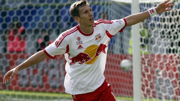 Ein Fußballspieler im Trikot von Red Bull jubelt vor einem Tornetz.