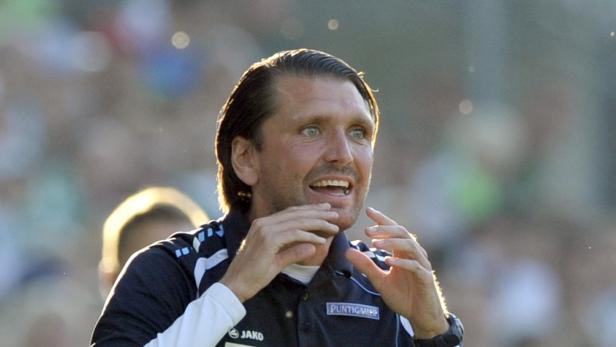 Ein Trainer gestikuliert während eines Fußballspiels.