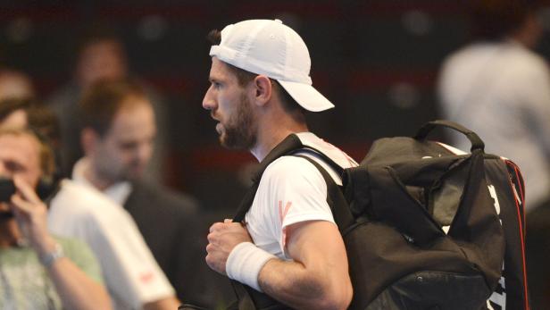 Ein Tennisspieler mit Kappe und Sporttasche im Profil.