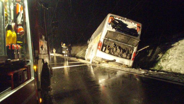 Ein verunglückter Bus steht nachts auf einer glatten Straße, umgeben von Rettungskräften.