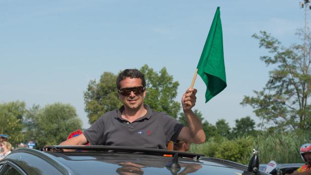 Ein Mann steht in einem Auto und schwenkt eine grüne Flagge.