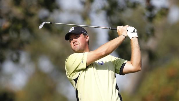 Ein Golfspieler schwingt seinen Schläger vor einem unscharfen Hintergrund.