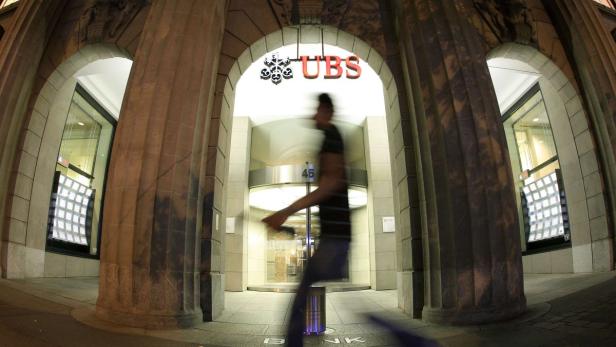 Ein verschwommener Mann geht vor einer UBS-Filiale vorbei.