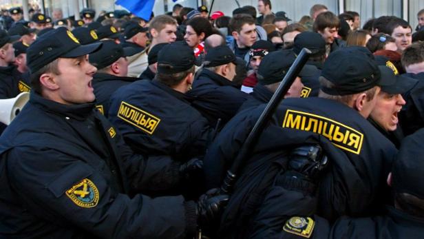 Eine Menschenmenge, darunter uniformierte Polizisten mit der Aufschrift „МІЛІЦЫЯ“.