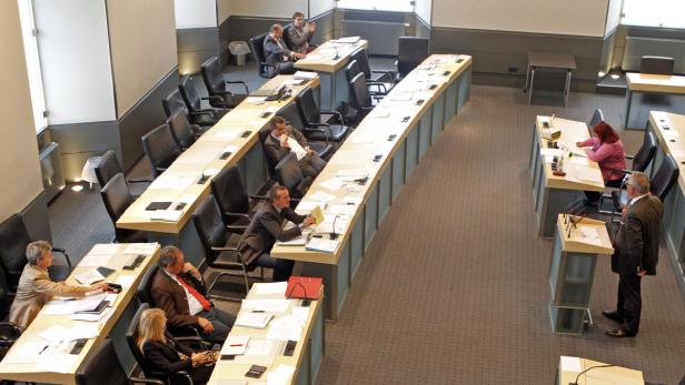 Eine Sitzung mit mehreren Personen an Tischen in einem Konferenzraum.