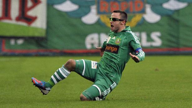 Ein Fußballspieler in grüner Uniform jubelt auf dem Rasen.