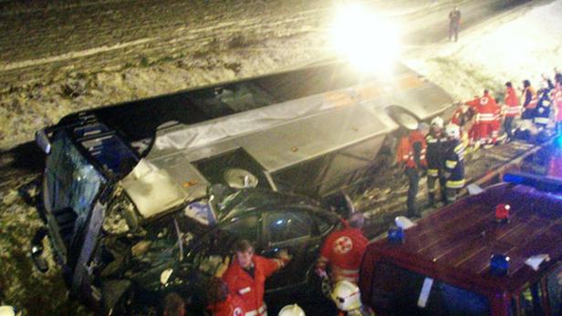 Ein Bus liegt nach einem Unfall auf der Seite, Rettungskräfte sind vor Ort.
