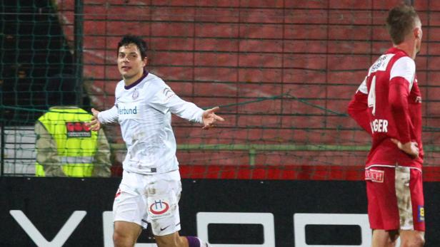 Ein Fußballspieler jubelt auf dem Spielfeld mit ausgestreckten Armen.