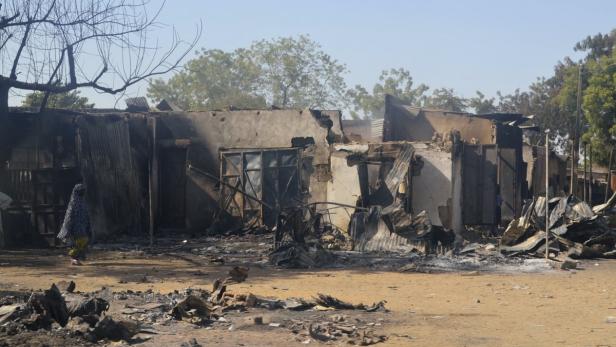 Eine Frau geht an einem zerstörten Gebäude vorbei, das durch ein Feuer beschädigt wurde.