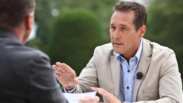 Ein Mann in einem beigen Sakko gestikuliert während eines Interviews.