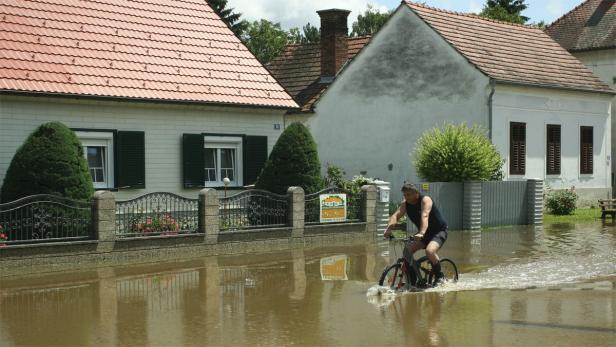 Ein Mann fährt mit dem Fahrrad durch eine überflutete Straße.