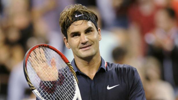 Roger Federer hält einen Tennisschläger und lächelt.