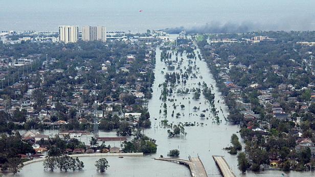 Luftaufnahme einer überfluteten Stadt, bei der das Wasser bis zu den Dächern der Häuser reicht.