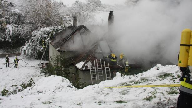Feuerwehrleute bekämpfen einen Hausbrand im Schnee.