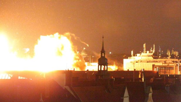 Eine Explosion erhellt den Nachthimmel über einer Stadt.