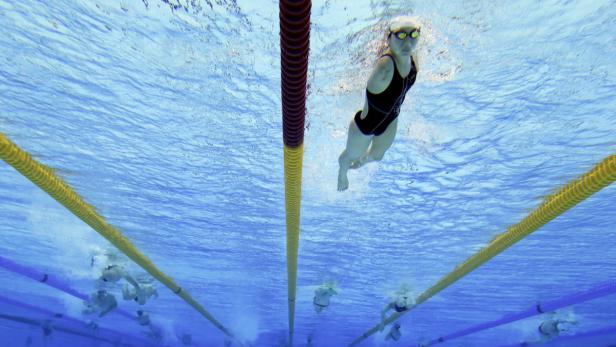 Eine Schwimmerin unter Wasser in einem Schwimmbecken mit mehreren Bahnen.