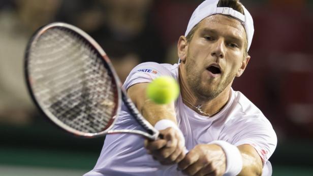 Ein Tennisspieler schlägt einen Ball mit seinem Schläger.