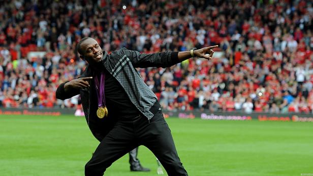 Usain Bolt feiert mit seinen Goldmedaillen vor einer jubelnden Menge.