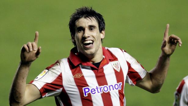 Ein lächelnder Fußballspieler von Athletic Bilbao zeigt mit beiden Zeigefingern nach oben.