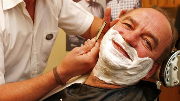 Ein Mann bekommt in einem Friseursalon eine Rasur mit einem Rasiermesser.