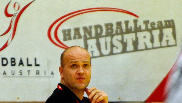 Ein Mann steht vor einem Banner des Handball-Teams Austria.