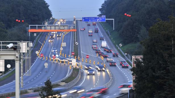 Mehrspurige Autobahn mit regem Verkehr in der Dämmerung.