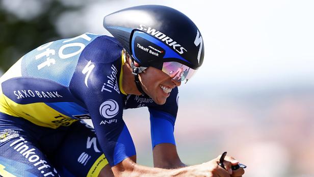 Ein Radrennfahrer mit aerodynamischem Helm und Trikot der Sponsoren Saxo Bank und Tinkoff Bank.