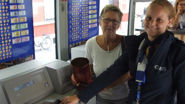 Eine ältere Frau und eine Bankangestellte stehen an einem Automaten der Oberbank.