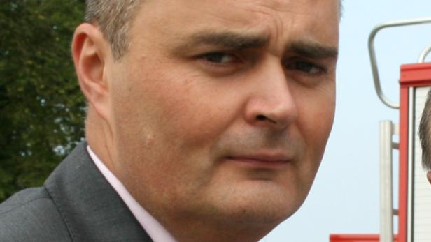 Porträt eines Mannes in einem grauen Anzug.